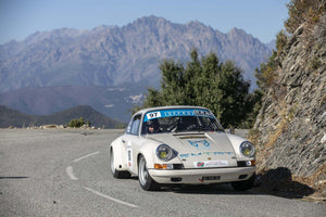 Original Porsche with Cibié Bi-Iodes headlights on mountain road during a rally event.