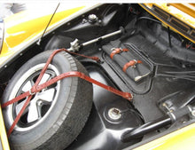Load image into Gallery viewer, Porsche 911 spare tire held by leather straps in vehicle trunk.